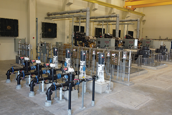 Industrial pump station with piping, valves, control panels, and equipment inside a large facility