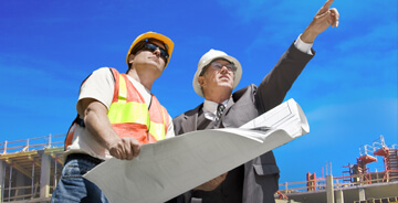 Two men discussing blue prints at a job site